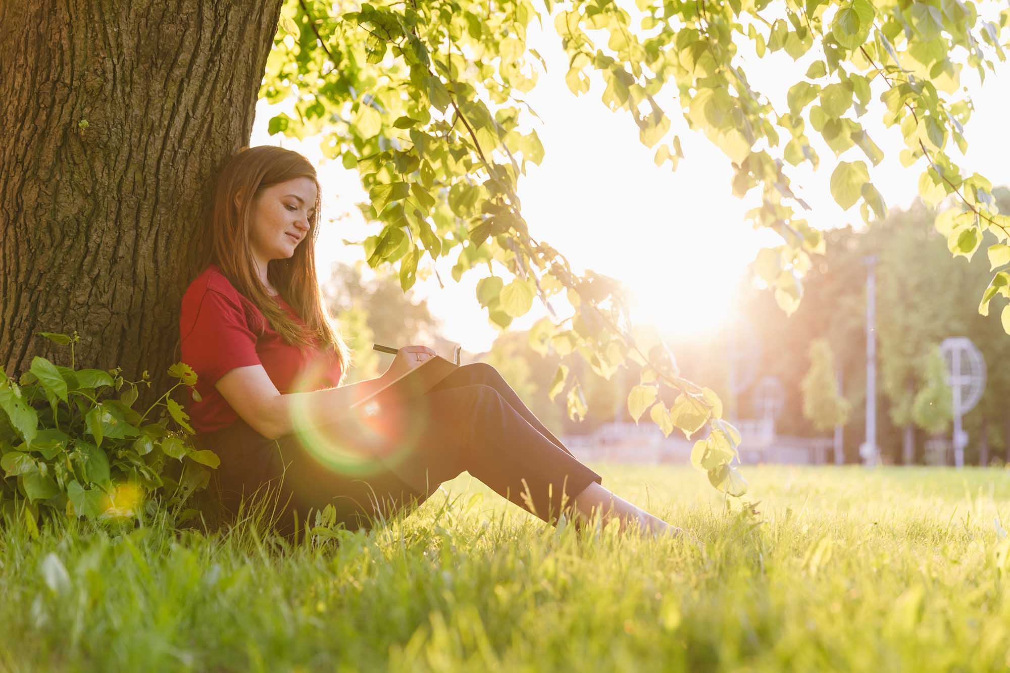 Woman writing in a notebook outdoors after life coach guidance.