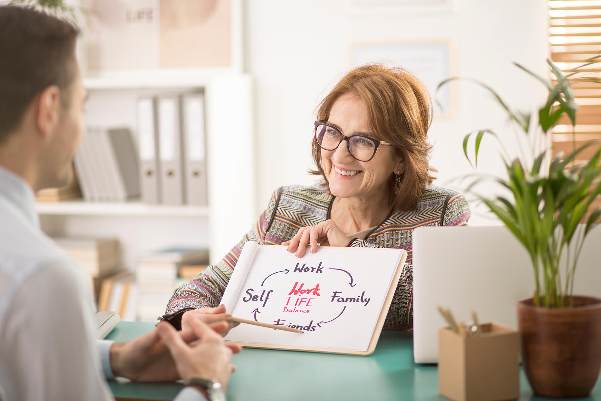 Life coach helping person balance work and life on a scale