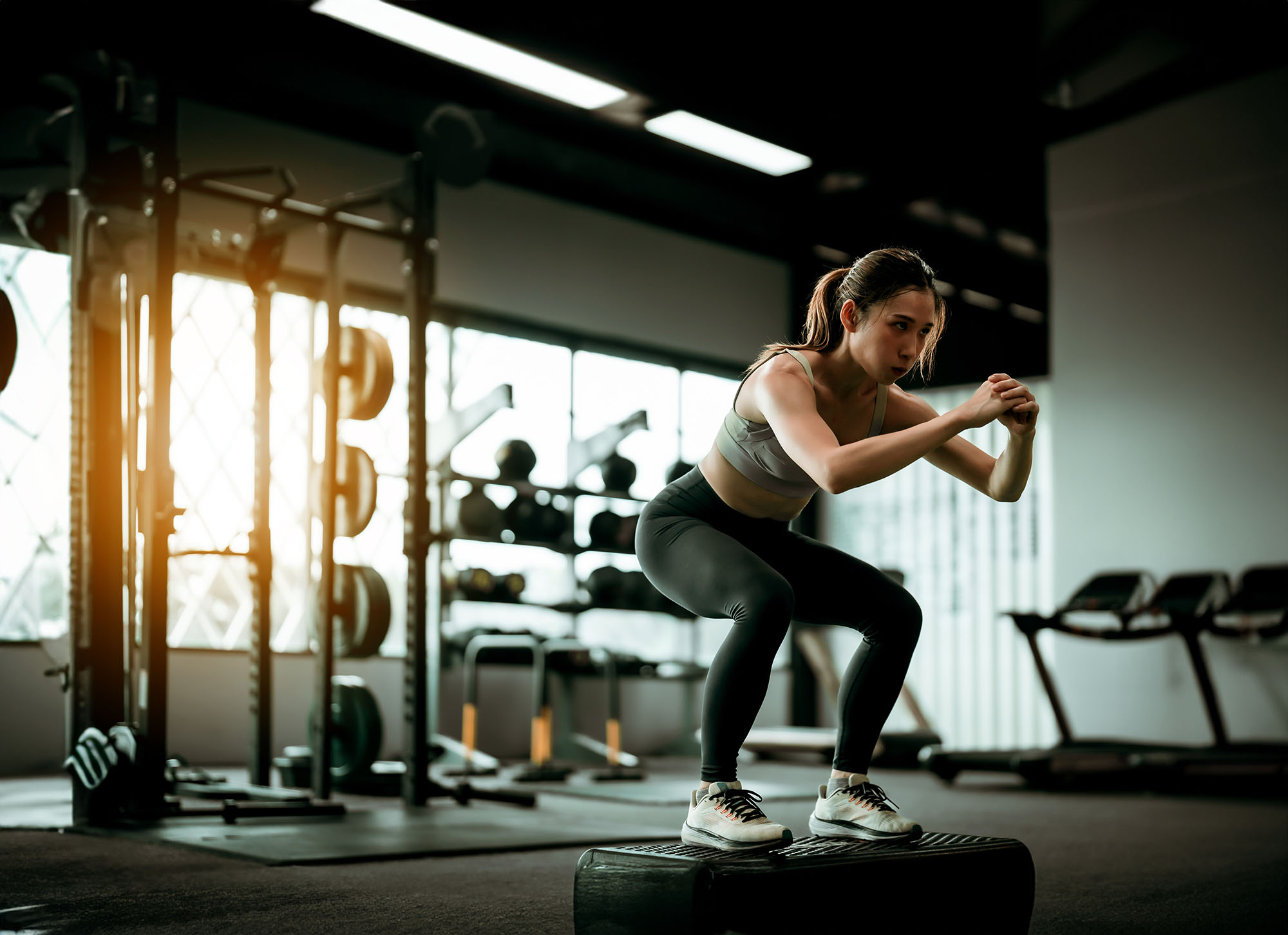 A woman is perfecting her exercise form for squats as part of her self-development plan