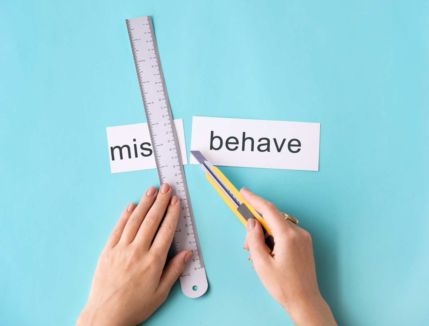 Person cutting the word “misbehave” to separate it into two parts, representing how limiting beliefs can be challenged and reframed.