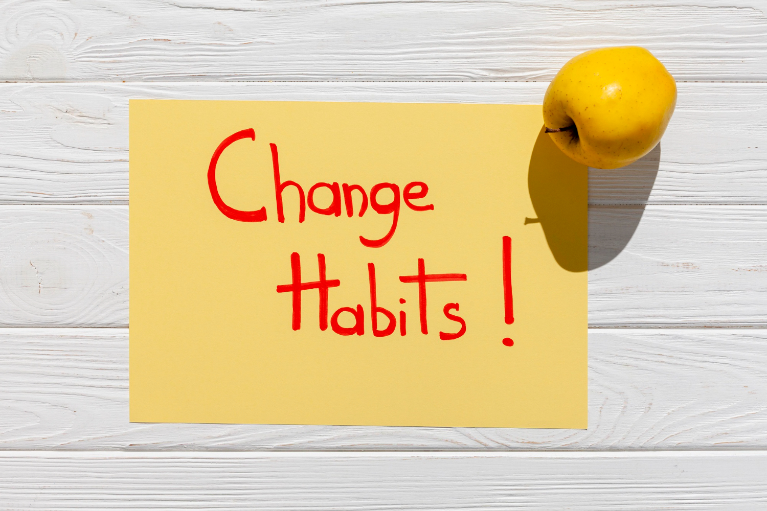 Yellow paper with the words "Change Habits!" and an apple beside it, promoting the idea of starting healthy habits.