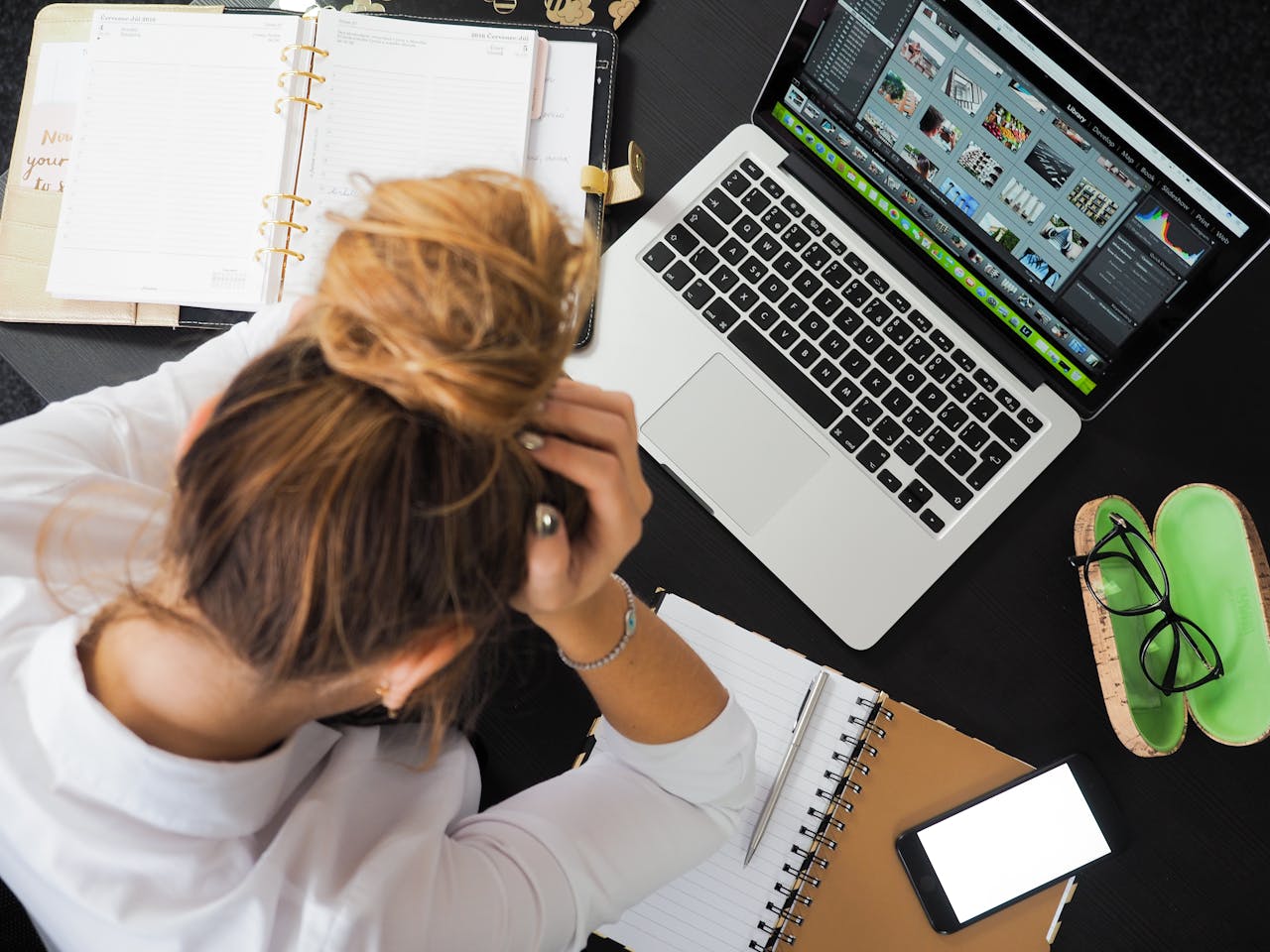Woman at a desk holding her head, showing a common sign of anxiety at work