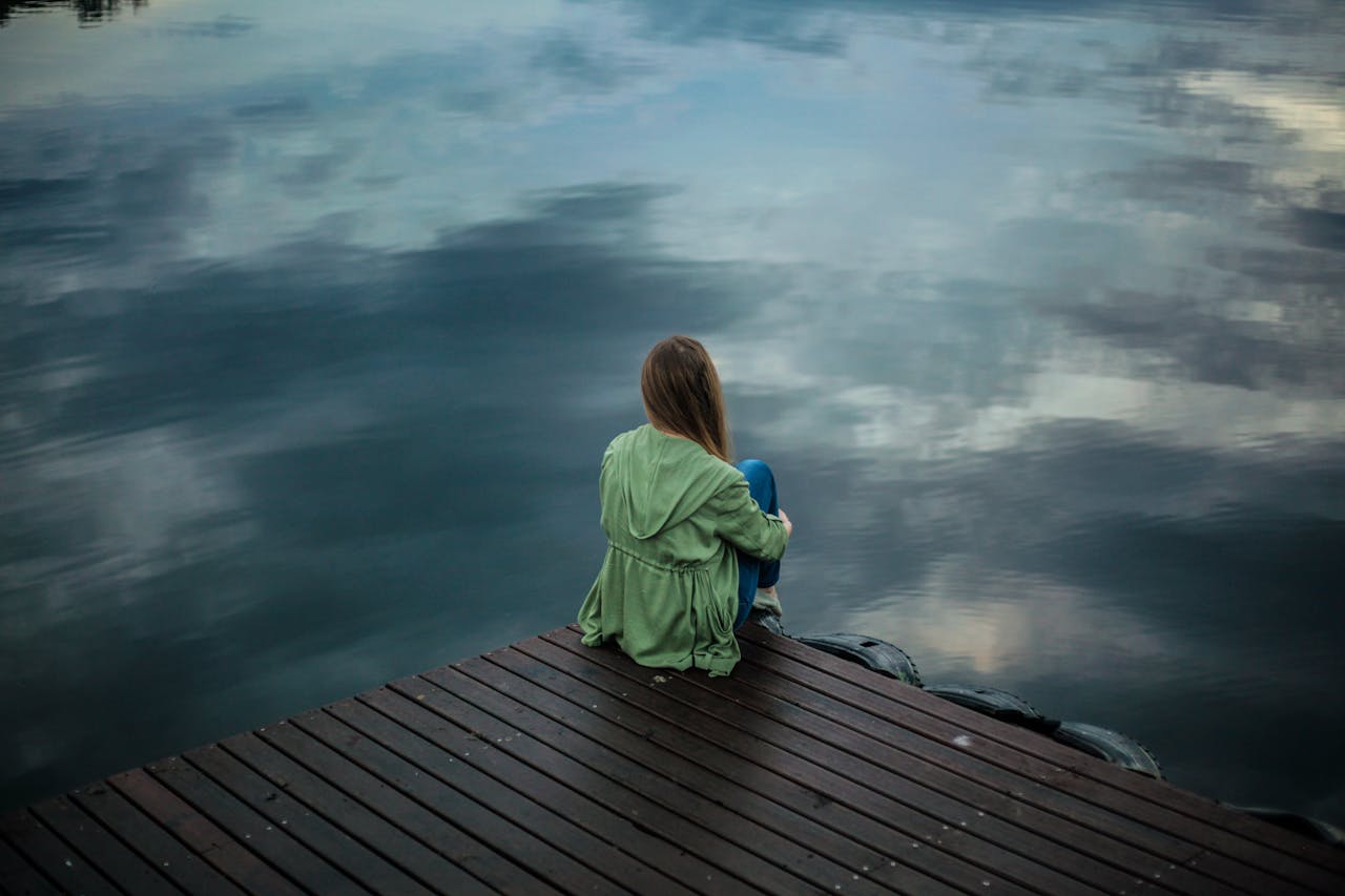 Person sitting alone by the water, linked to anxiety caused by isolation or overthinking